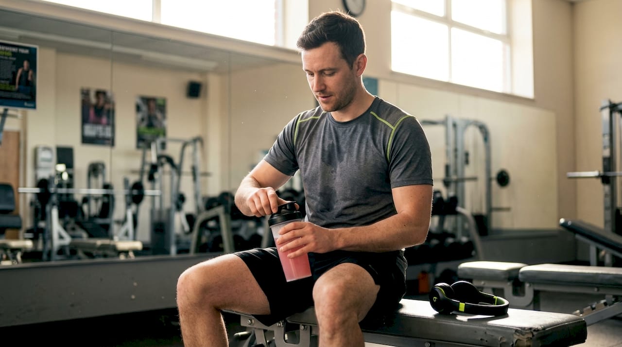 Man preparing pre-workout drink at gym