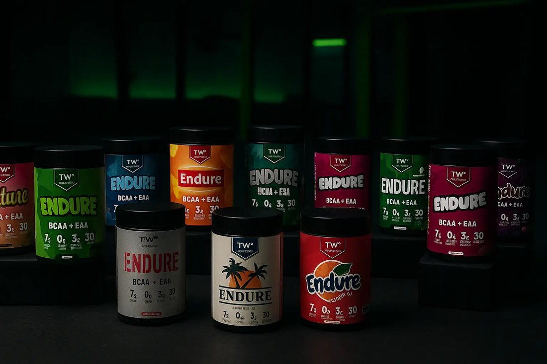 multiple tubs of TWP Endure BCAA + EAA supplements arranged in rows on a dark gym floor