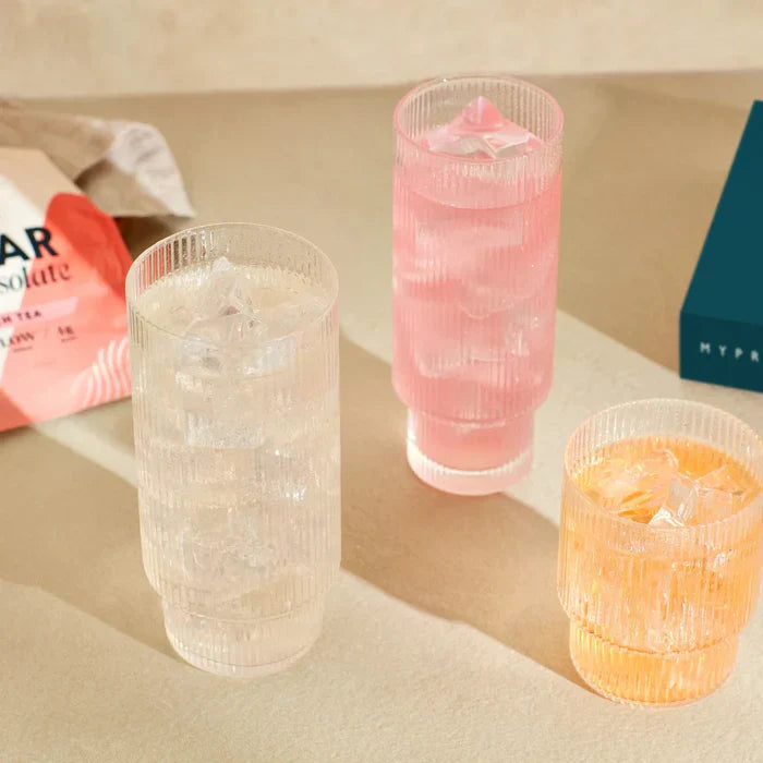 Three ribbed glass tumblers with beverages and ice for MyProtein Clear Whey Isolate sports nutrition awards
