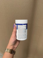 White USN Ashwagandha container with blue label, hand holding with purple nails