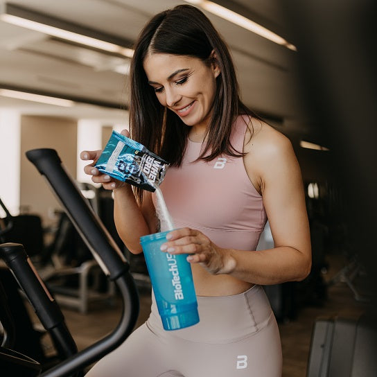 Woman pouring protein powder into shaker with Biotech USA Iso Whey Zero Lactose Free