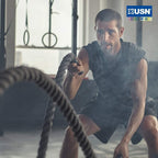 Man in workout gear using battle ropes with USN Ashwagandha root extract for energy