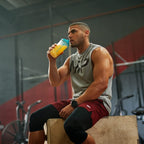 Fitness enthusiast in grey tank top and red shorts drinking clear whey isolate protein from shaker bottle