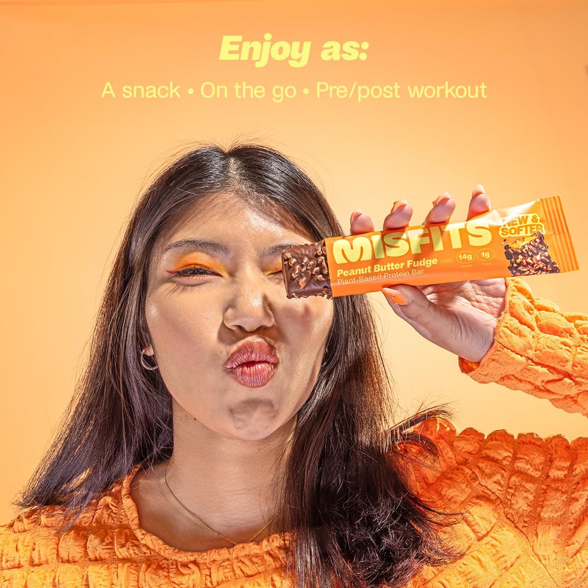 Woman holding a Misfits Plant-Based Protein Bar with Peanut Butter Fudge flavor