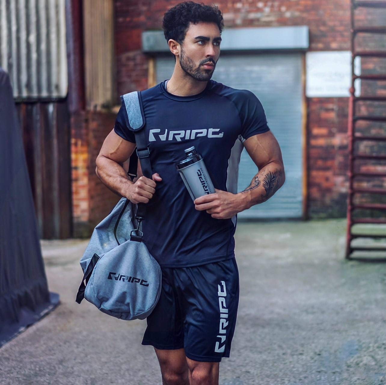 Man in athletic wear holding a duffel bag and water bottle with RIPT Contrast Performance T-Shirt XL