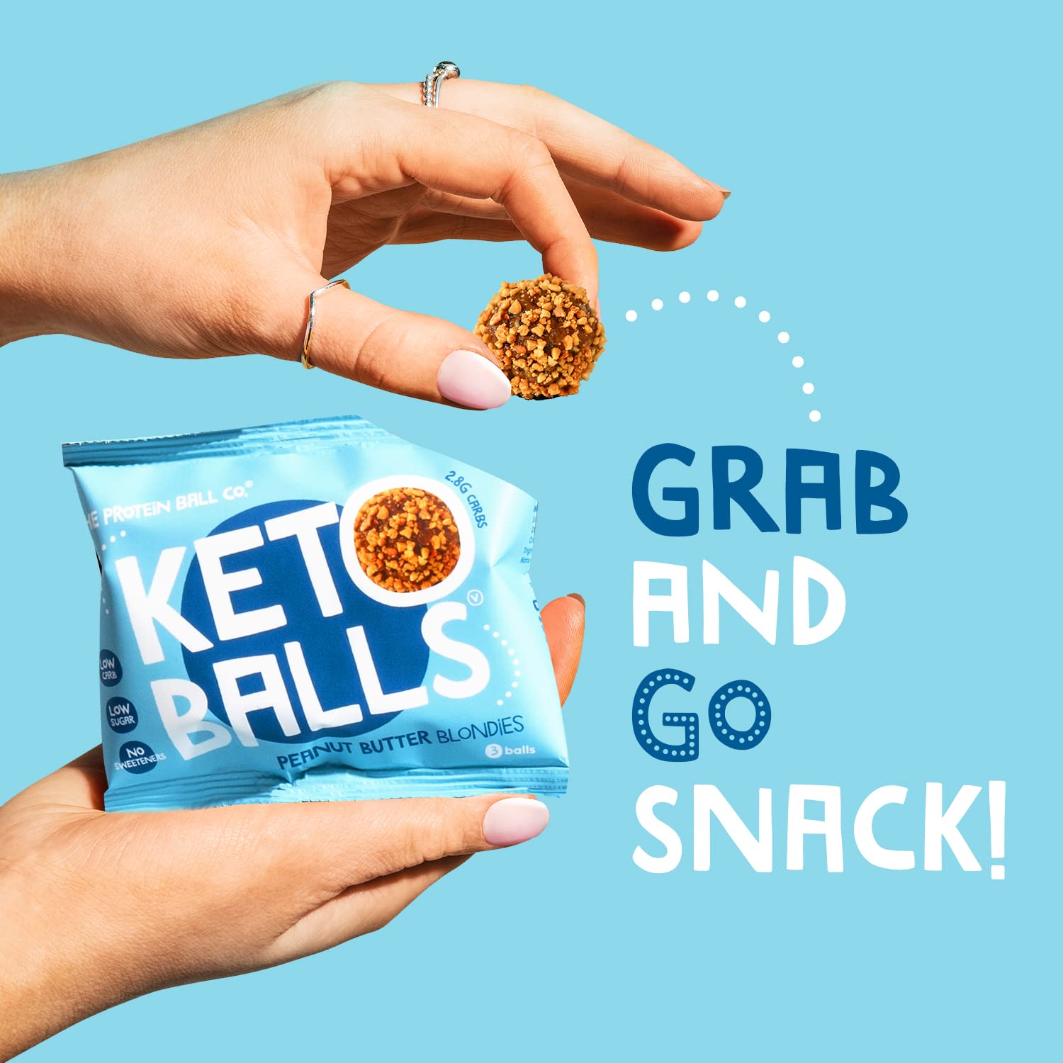 Hands holding a package of Keto Balls and a protein ball peanut butter snack