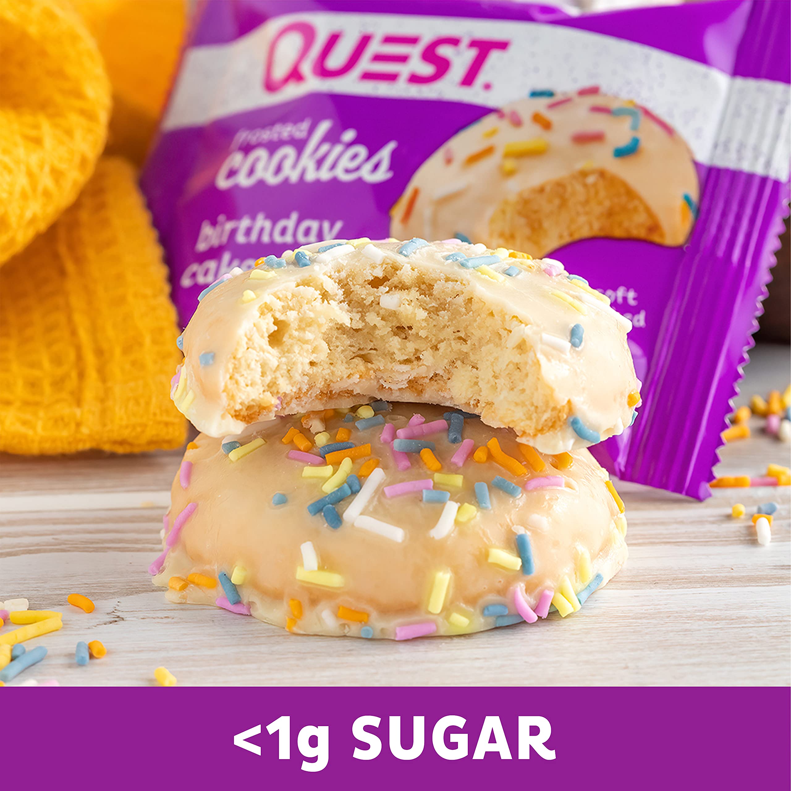Quest Frosted Cookies twin packs with chocolate cake flavor, one broken in half with sprinkles