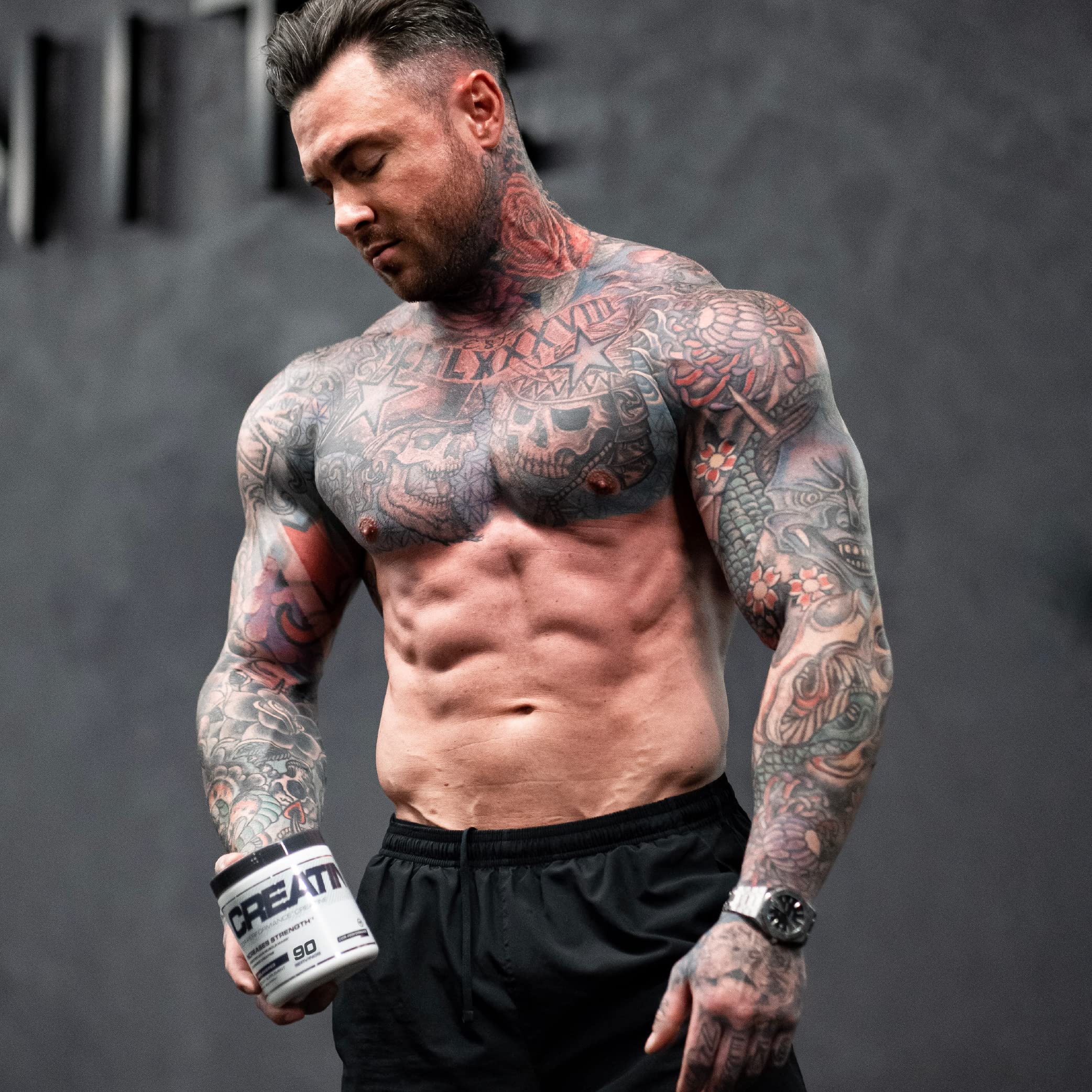Muscular tattooed man holding Cellucor Cor-Performance Creatine for superior mixability