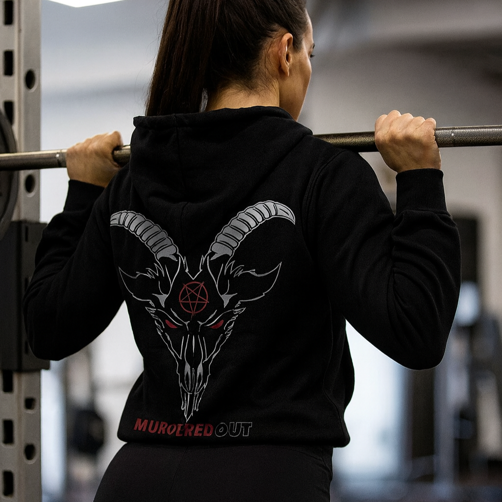 Person wearing a black hoodie with a goat skull design in a gym setting