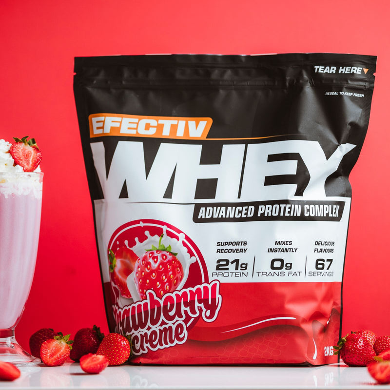 Black and red Effectiv Nutrition Whey Protein bag with strawberry milkshake and fresh strawberries for lean muscle
