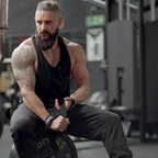 Muscular man with beard lifting RDX Training Weight wrist straps with wicking properties