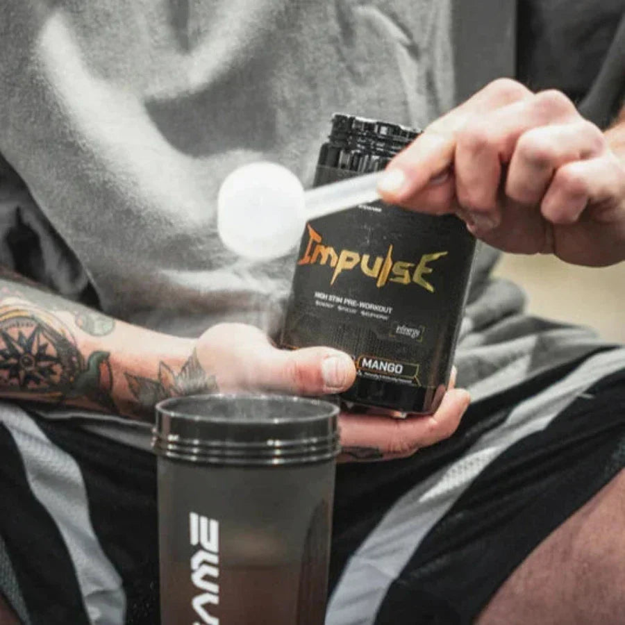 Person scooping mango-flavored Endgame Impulse pre-workout for laser-sharp focus and explosive energy